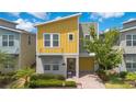 Inviting two-story home with a yellow facade, manicured landscaping, and a paver driveway at 2736 Bookmark Dr, Kissimmee, FL 34746
