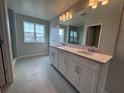 Modern bathroom with double sink vanity, large mirror, and a shower with a glass door at 5069 Rain Shadow Dr, Saint Cloud, FL 34772