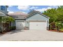 View of the three-car garage featuring stone accents and a brick paved driveway at 7508 Lake Albert Dr, Windermere, FL 34786