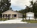 Charming home featuring a gated driveway, metal garage, and a cozy front porch at 9650 Nw Gainesville Rd, Ocala, FL 34475