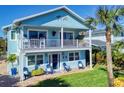 Two-story light blue house with a balcony, and nicely landscaped lawn at 110 Surf St, New Smyrna Beach, FL 32169