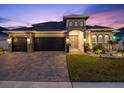 Beautiful home featuring a paved driveway and three-car garage, complemented by a stone-accented facade and lush landscaping at 489 Avila Pl, Howey In The Hills, FL 34737