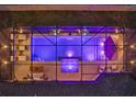 Aerial view of an illuminated rectangular pool surrounded by lounge chairs and a contemporary metal structure at 489 Avila Pl, Howey In The Hills, FL 34737