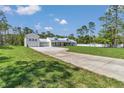 Beautiful home featuring a pristine white exterior, complemented by lush green lawns and a concrete driveway at 12009 Sw 61St Place Road, Ocala, FL 34481