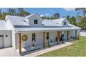 Beautiful white farmhouse exterior with metal roof, wooden columns, and manicured landscaping at 12009 Sw 61St Place Road, Ocala, FL 34481