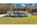 Modern farmhouse exterior with dark-framed windows, wooden pillars, and expansive green lawn at 8267 Sw 129Th Terrace Rd, Dunnellon, FL 34432