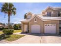 Inviting home featuring a two-car garage, neutral stucco exterior, and a well-maintained front lawn with palm tree at 7700 Carriage Homes Dr # 4, Orlando, FL 32819