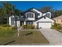 Two-story house with black and white exterior, lush landscaping, and a paved driveway at 4431 Rock Hill Loop, Apopka, FL 32712