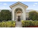 Front entryway with arched entry, lush landscaping, and a black front door at 1657 Carillon Park Dr, Oviedo, FL 32765