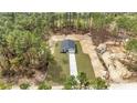 Aerial view of a modern home, nestled in a wooded area, highlighting its spacious surroundings and long driveway at 13516 Sw 78 Pl, Dunnellon, FL 34432