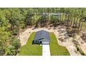 An aerial shot shows a new home with fresh landscaping and driveway in a serene, wooded setting at 13516 Sw 78 Pl, Dunnellon, FL 34432