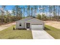 A modern single-story house with well-maintained lawn and a long driveway, surrounded by tall trees and nature at 13516 Sw 78 Pl, Dunnellon, FL 34432