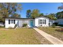 Charming home with a manicured front yard featuring a blue front door and black trimmed windows and roof at 1311 Hartley Ave, Deltona, FL 32725