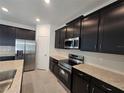 Modern kitchen with dark cabinetry, stainless steel appliances, and granite countertops at 1200 Bear Oak Ln, Deland, FL 32720