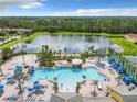 Aerial view of community pool with multiple pools, lounge chairs, gazebo, tennis courts and a large pond surrounded by trees at 2948 Banana Palm Dr, Kissimmee, FL 34747