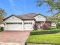Charming single-story home featuring a three-car garage, brick driveway, clay tile roof and manicured landscaping at 8914 Dove Valley Way, Davenport, FL 33896