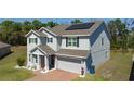 A two-story home showcasing solar panels on the roof and a brick driveway at 678 Fiddlesticks Dr, Davenport, FL 33837