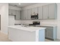 Modern kitchen featuring gray cabinetry, stainless steel appliances, and a center island with sink at 9097 Wildlight Trl, Wildwood, FL 34785