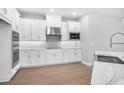 Modern kitchen with stainless steel appliances, sleek white cabinets, and wood-look floors at 2982 Arranmore Dr, Ormond Beach, FL 32174