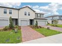 Modern townhomes feature a brick walkway, manicured landscaping, and attached garages, offering curb appeal at 16332 Happy Eagle Dr, Clermont, FL 34714