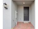 Covered porch with red brick flooring leads to a modern, dark front door at 16332 Happy Eagle Dr, Clermont, FL 34714