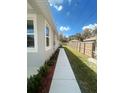 Narrow side yard with a tidy walkway, lush green grass, and a well-maintained wooden fence at 388 Chinaberry Ave, Oviedo, FL 32765