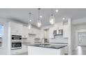 Modern kitchen with stainless steel appliances, white cabinetry, a black countertop island, and pendant lighting at 4723 Coral Harbour Rd, Kissimmee, FL 34758
