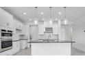 Modern kitchen with stainless steel appliances, white cabinetry, a black countertop island, and pendant lighting at 4723 Coral Harbour Rd, Kissimmee, FL 34758