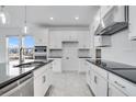 Well-lit kitchen featuring stainless steel appliances, white cabinets with black counters and tile backsplash at 4723 Coral Harbour Rd, Kissimmee, FL 34758