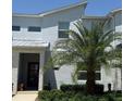 Modern two-story townhome features a red front door, a manicured lawn, and lush landscaping at 8943 Cabot Cliffs Dr, Davenport, FL 33896