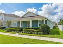 Charming single-story blue home with a well-manicured lawn, neat shrubbery, and a concrete walkway at 15542 Sunquat Dr, Winter Garden, FL 34787