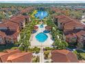 A bird's-eye view of a beautiful community with a pool, palm trees, lush landscaping, and a serene lake with a fountain at 5578 Metrowest Blvd # 101, Orlando, FL 32811