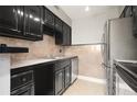 Kitchen featuring stainless steel appliances, dark cabinetry, and tile backsplash at 5929 Windhover Dr # A02, Orlando, FL 32819