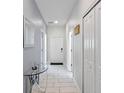Bright hallway featuring a glass table, tiled floor, and white doors, leading to other areas of the house at 1574 Slice Way, Davenport, FL 33896