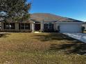 One-story house featuring a white garage door and lush green lawn at 9875 Sw 55Th Ct, Ocala, FL 34476