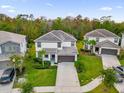 Aerial shot of a two-story white house with well-manicured lawn, mature trees, and a driveway with a two-car garage at 4571 Cabello Loop, Kissimmee, FL 34746