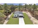 Inviting exterior of home with a lush green lawn and a long driveway surrounded by a natural landscape at 12386 Sw 89Th St, Dunnellon, FL 34432