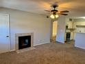 Cozy living room with fireplace, ceiling fan, and view into kitchen area with modern appliances at 485 Forestway Cir # 202, Altamonte Springs, FL 32701