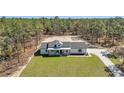 Aerial view of a modern white farmhouse with black trim on a large lot surrounded by trees at 8827 Sw 137Th Ct, Dunnellon, FL 34432