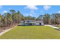 Stunning white farmhouse with black trim, wooden columns, and a lush green front lawn at 8827 Sw 137Th Ct, Dunnellon, FL 34432