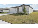 Inviting single-story home featuring a two-car garage, and neutral color scheme with lawn at 1324 Oak Valley Dr, Auburndale, FL 33823