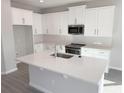 Bright kitchen featuring white cabinets, stainless steel appliances, and a large center island with sink and counter space at 576 Pothos St, Apopka, FL 32703