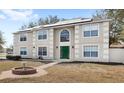 Two-story home featuring a green door, trimmed windows, solar panels, and front yard landscaping at 800 Daybreak Dr, Fruitland Park, FL 34731
