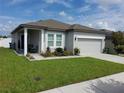Inviting one-story home with a manicured lawn, attractive landscaping, and a two-car garage at 881 Orchid Grove Blvd, Davenport, FL 33837
