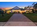 Home exterior at dusk with brick driveway and landscape lighting at 6550 Cartmel Ln, Windermere, FL 34786