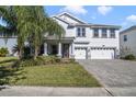 Two-story house with gray exterior, three-car garage, and a paved driveway at 1402 Olympic Club Blvd, Champions Gate, FL 33896
