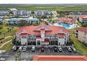 Well-maintained condo building showcasing lush landscaping, ample parking, and a vibrant red tile roof at 445 Bouchelle Dr # 202, New Smyrna Beach, FL 32169