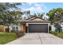 Tan house with orange door, dark brown garage door, and landscaped lawn at 1910 Rogers Ave, Maitland, FL 32751