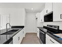Modern kitchen featuring white cabinetry, black countertops, and sleek appliances at 367 Sequoia Dr, Lake Wales, FL 33859
