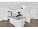 Bright kitchen featuring white cabinets, gray granite counters and island with stainless steel appliances at 410 Sequoia Dr, Lake Wales, FL 33859